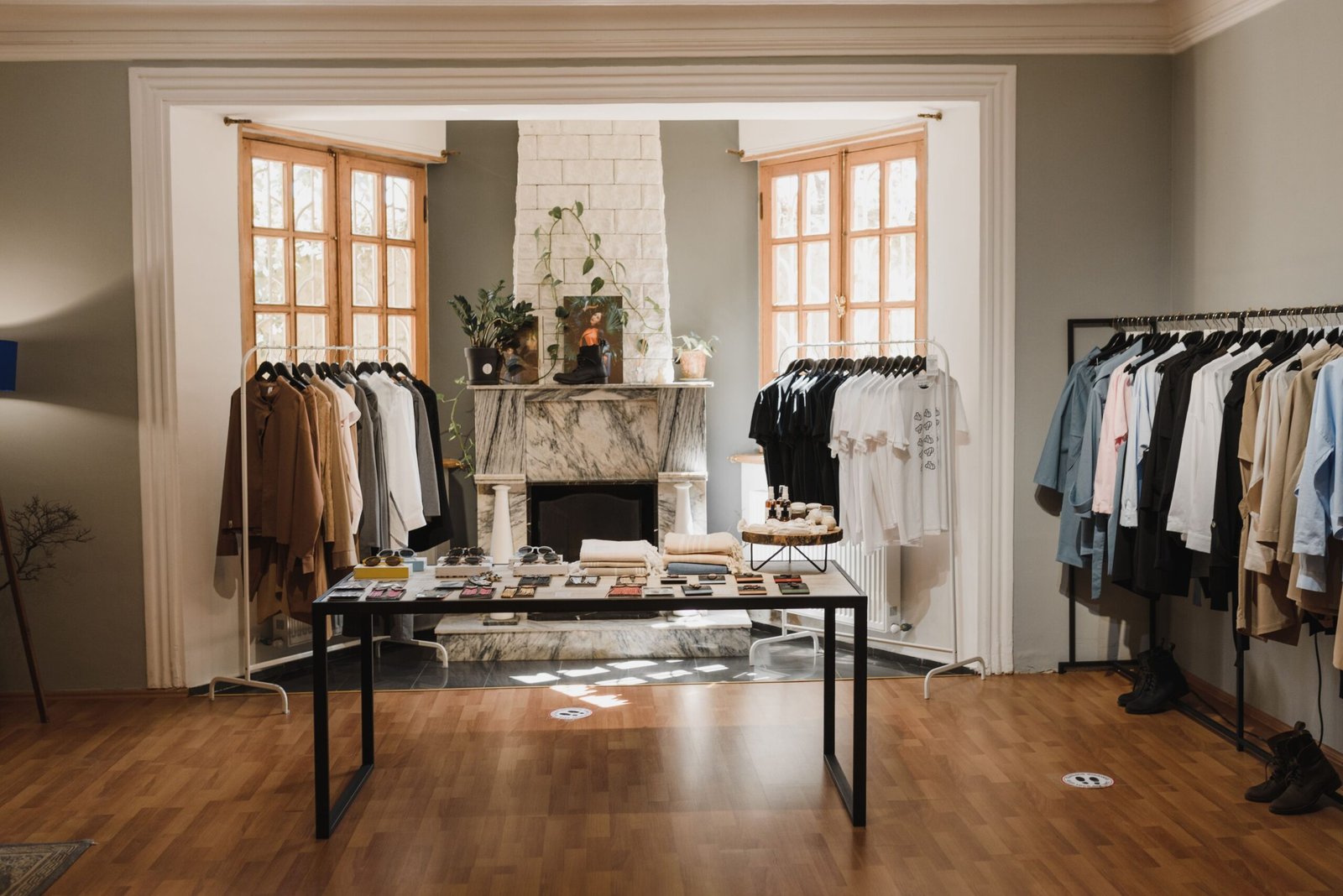 Modern clothing boutique with neatly arranged apparel on clothing racks, a central display table with accessories, and a bright, stylish interior.