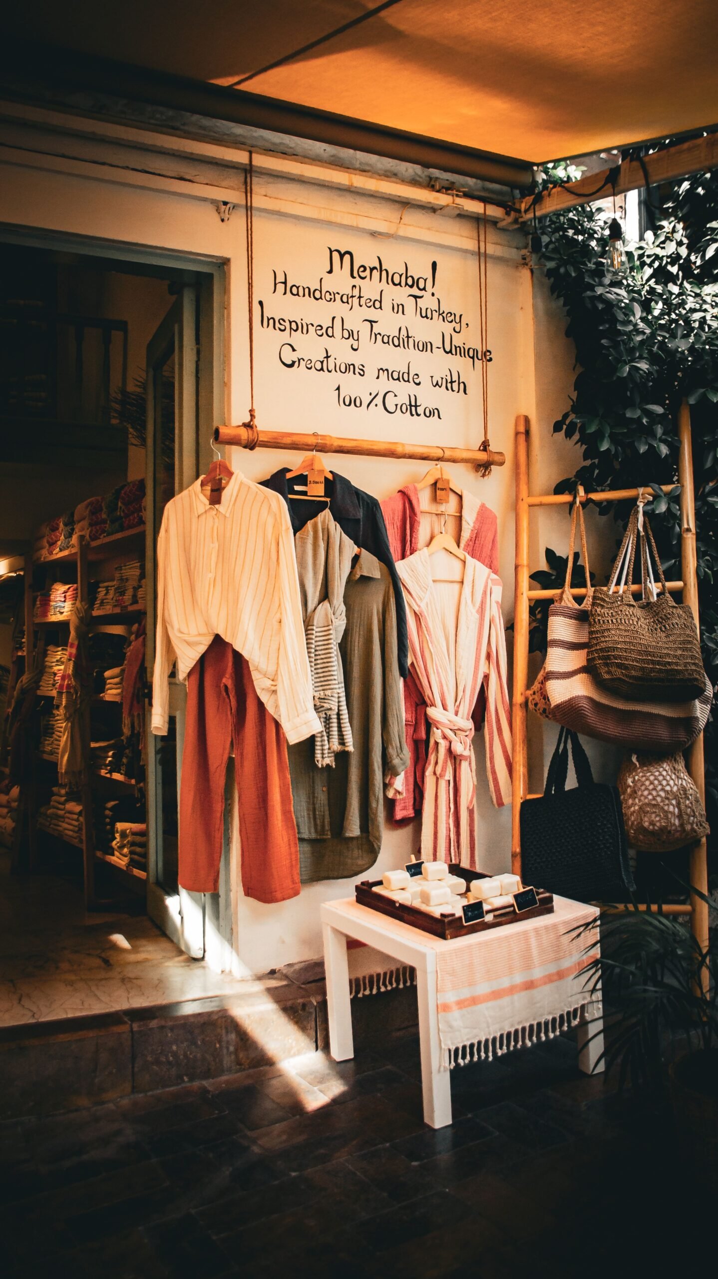 Cozy boutique entrance displaying women's clothing, woven handbags, and handmade accessories in a warm, inviting retail setting.